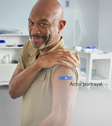 Actor portrayal of an adult male with his sleeve rolled up with a Pfizer band aid on his arm