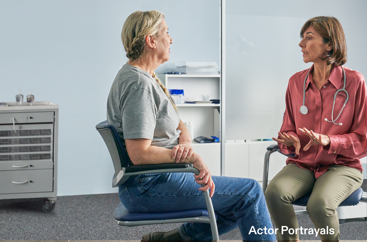 Actor portrayal of an adult female doctor talking with a female patient in a doctor's office