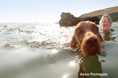 Actor portrayal of an older woman swimming in a lake with a brown dog