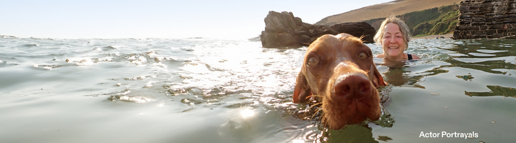 Actor portrayal of an older woman swimming in a lake with a brown dog