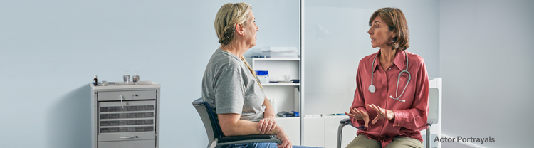 Actor portrayal of an adult female doctor talking with a female patient in a doctor's office