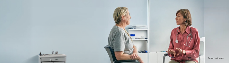 Actor portrayal of an adult female doctor talking with a female patient in a doctor's office