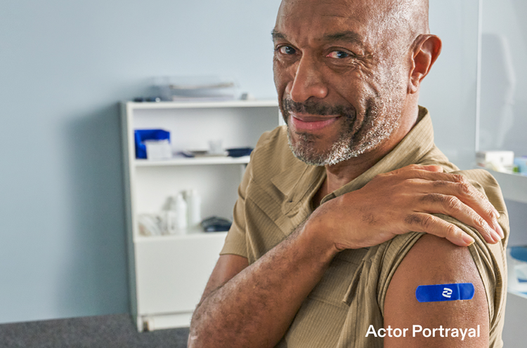 Actor portrayal of an adult male with his sleeve rolled up with a Pfizer band aid on his arm