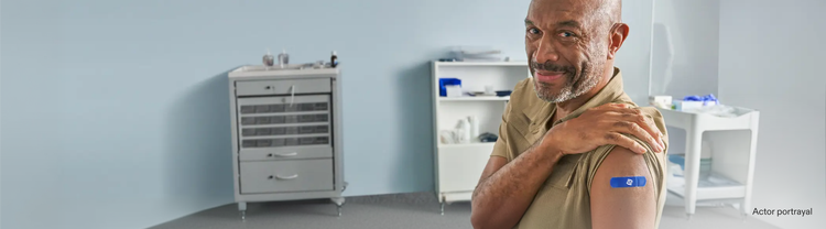 Actor portrayal of an adult male with his sleeve rolled up with a Pfizer band aid on his arm